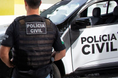 Policial civil ao lado de viatura