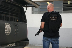 Policial civil ao lado de viatura