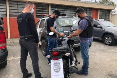 Policiais observam moto recuperada