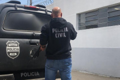 Policial civil empunhando arma ao lado de viatura