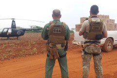 Policiais civis de costas, próximo veículo com contrabando e helicóptero da polícia