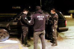 Policiais civis reunidos, ao lado de viatura