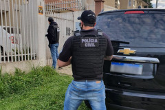 Policiais civis na calçada, em frente ao local de busca
