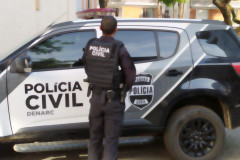 Policial civil ao lado de viatura
