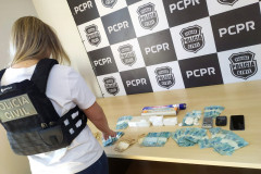 Policial civil de costas organizando materiais apreendidos sobre uma mesa
