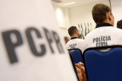 Policiais civis de costas, sentados. Em primeiro plano, nome PCPR