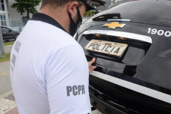 Policial civil fechando tampa do porta-malas de viatura