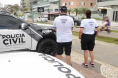 Dois policiais civis ao lado de viaturas observam o movimento no litoral