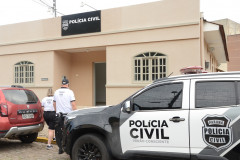 Dois policiais civis ao lado de viatura, entrando na delegacia de Guaratuba