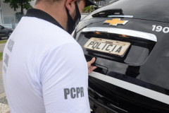 Policial civil fechando o porta malas da viatura
