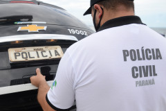Policial civil fechando tampa de porta-malas de viatura