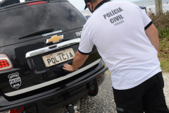 Policial civil fechando tampa do porta-malas de viatura