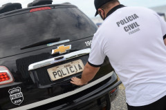 Policial civil fechando tampa do porta-malas de viatura