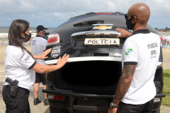 Policiais civis fechando tampa de porta-malas de viatura