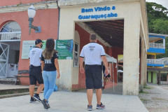 Três policiais civis de costas, andando.