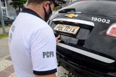 Policial fechando o porta malas da viatura