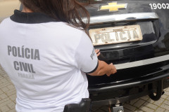 Policial civil fechando tampa do porta-malas de viatura