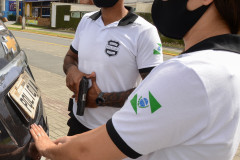 Uma policial civil fecha tampa do porta-malas de viatura enquanto outro policial empunha arma