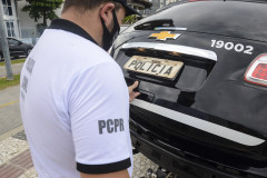 Policial civil fechando tampa de porta-malas de viatura