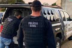 Dois policiais civis ao lado de viatura