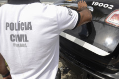 Policial civil fechando tampa do porta-malas de viatura