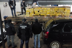 Policiais civis observando e descarregando caminhao com as drogas