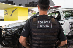 Policial civil ao lado de viatura