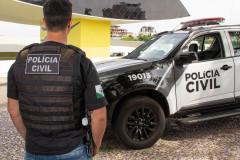 Policial civil ao lado de viatura