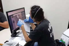 Policial civil observa, na tela de um computador, digitais recolhidas