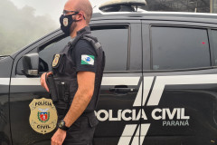 Policial civil ao lado de viatura