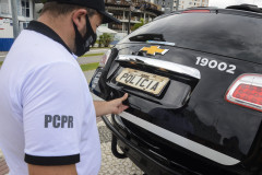Policial civil fechando tampa do porta-malas de viatura