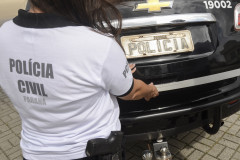 Policial civil fechando tampa de porta-malas de viatura