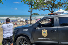 Policial civil ao lado de viatura, observa movimento dos veranistas
