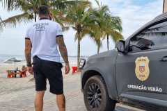 Policial civil ao lado de viatura observa o movimento dos veranistas