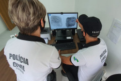 Dois policiais civis analisando impressões digitais 