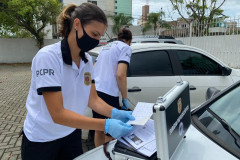 Duas papiloscopistas recolhendo impressões digitais em automóvel