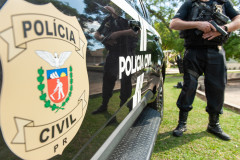 Policial civil empunha arma ao lado de viatura