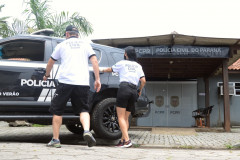 Dois policiais civis entrando em viatura em frente à delegacia de Pontal