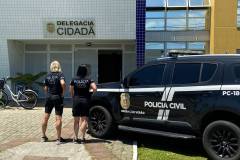 Duas policiais ao lado de viatura em frente à delegacia de matinhos
