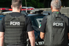 Dois policiais de costas ao lado de viatura
