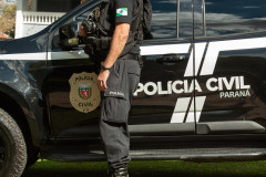 Policial civil ao lado de viatura