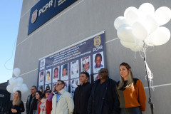 Policiais civis reunidos para fotografia. Ao fundo, banner com imagem dos desaparecidos