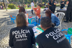 Dois policiais civis observam crianças brincando