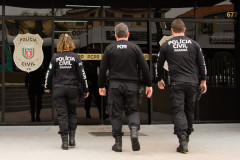 Tres policiais civis de costas entrando em delegacia
