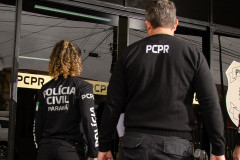 Dois policiais de costas entrando em delegacia