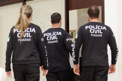 Três policiais de costas entrando em sala