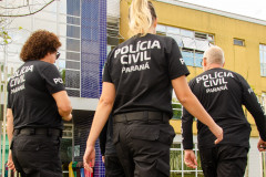 Três policiais em frente a delegacia