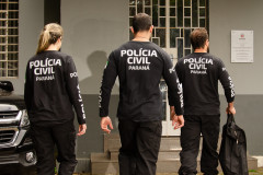 Três policiais civis em frente a delegacia
