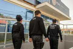 Três policiais civis em frente à delegacia
