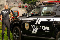 Policial civil ao lado de viatura